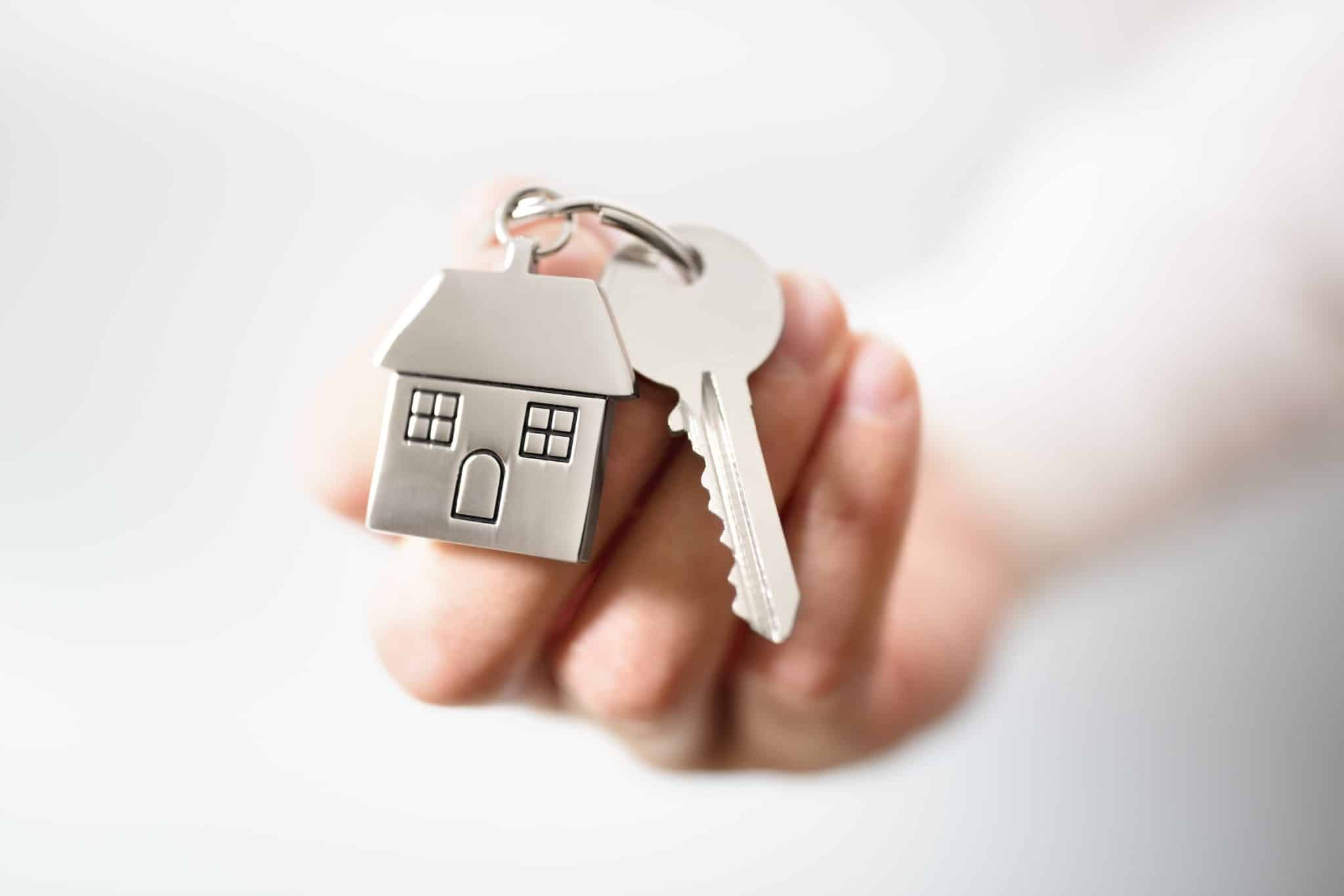 hand holding house key with house shaped keychain
