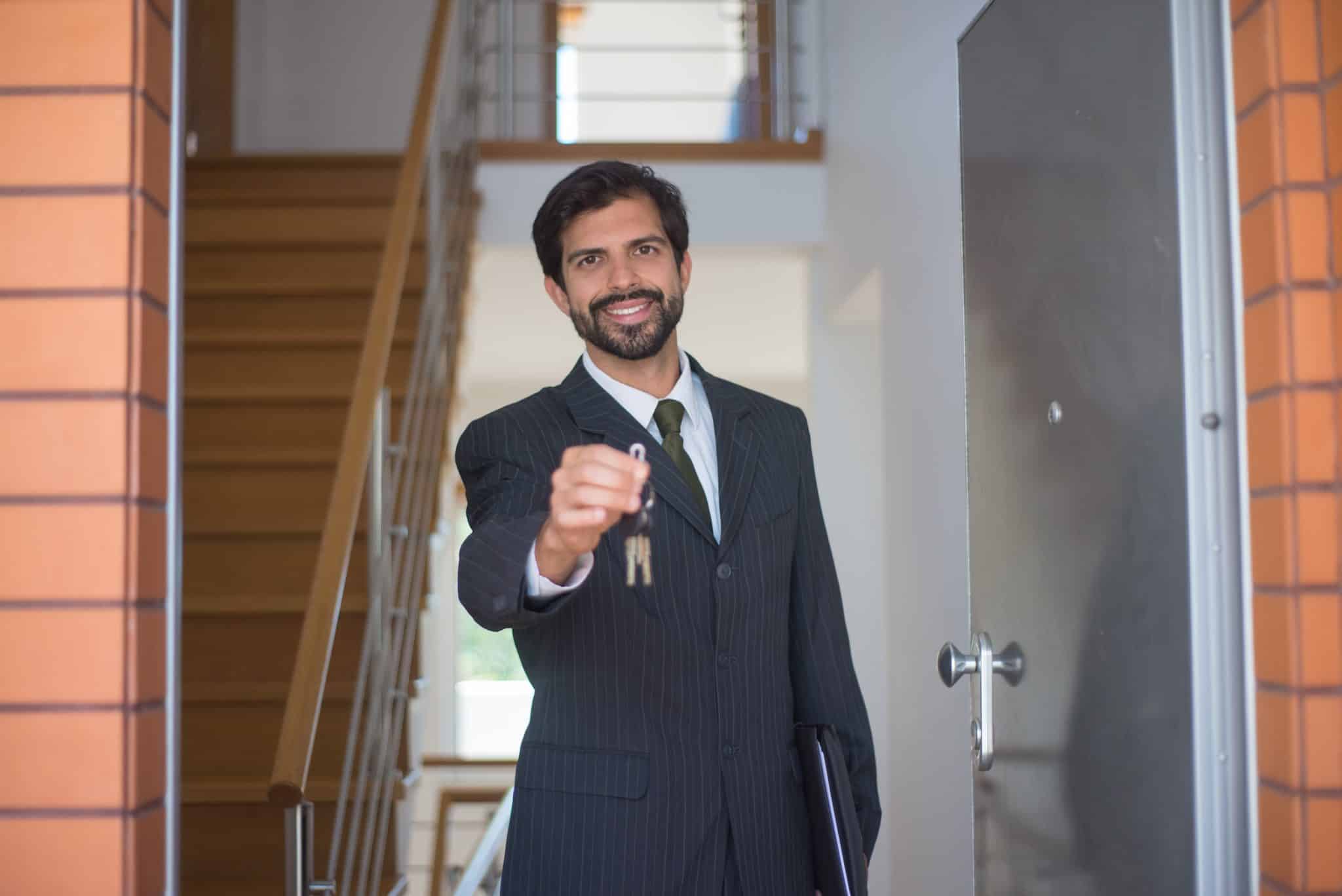 real estate agent standing in doorway of home and holding out set of keys